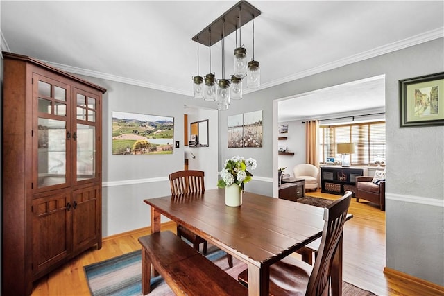 dining room featuring light wood-style floors, ornamental molding, and a chandelier