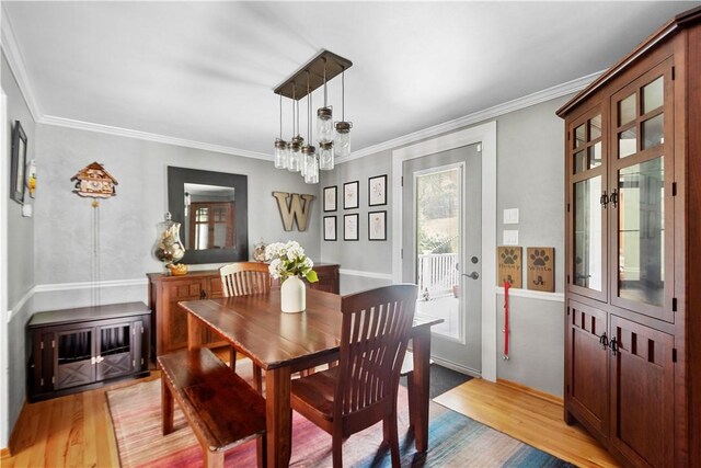 dining room featuring light wood-type flooring, crown molding, and an inviting chandelier