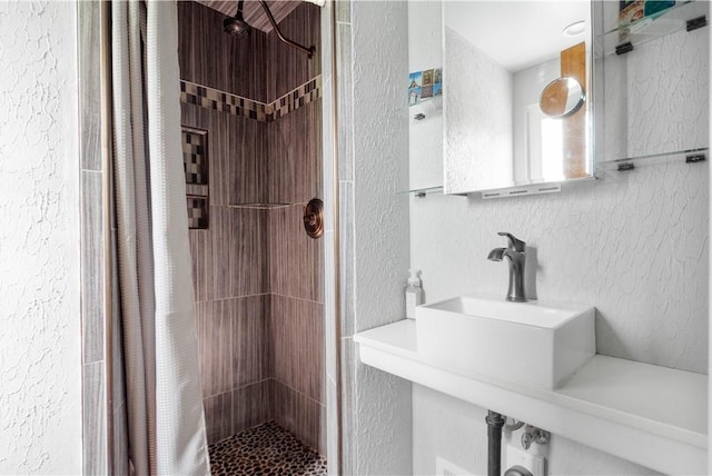 bathroom featuring a sink, a textured wall, and a shower stall