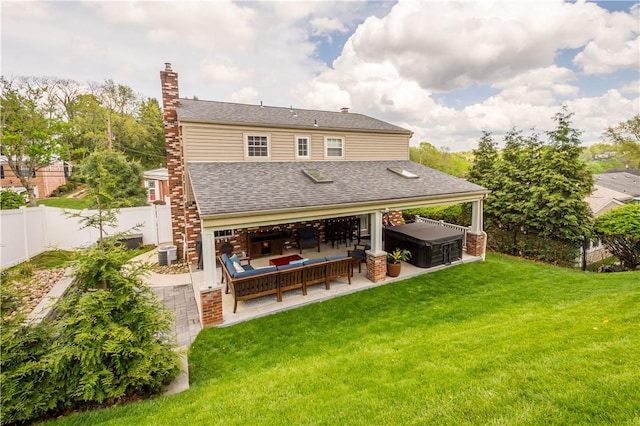 rear view of house with a fenced backyard, a shingled roof, a patio area, a hot tub, and a yard