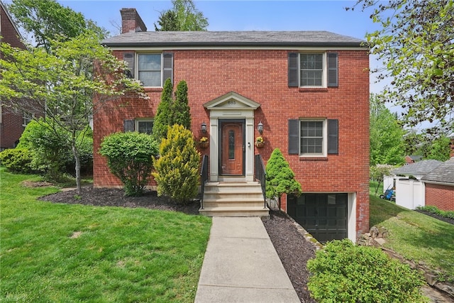 colonial house with brick siding, a chimney, a front lawn, and a garage