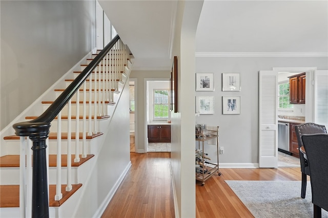 entrance foyer with crown molding, baseboards, stairway, plenty of natural light, and light wood-type flooring