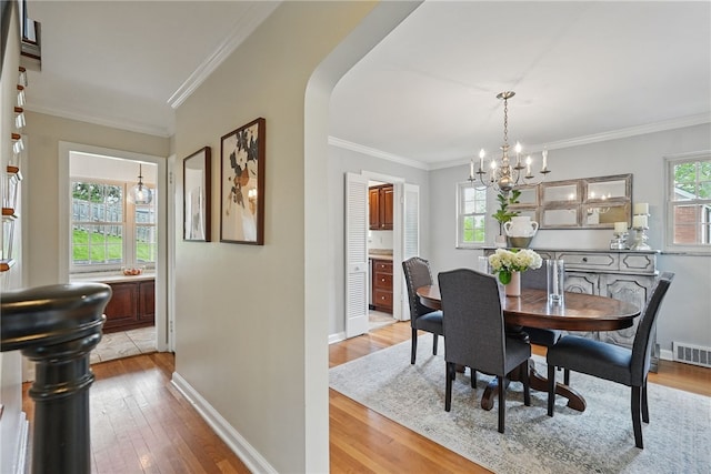 dining area with visible vents, ornamental molding, baseboards, light wood finished floors, and a notable chandelier