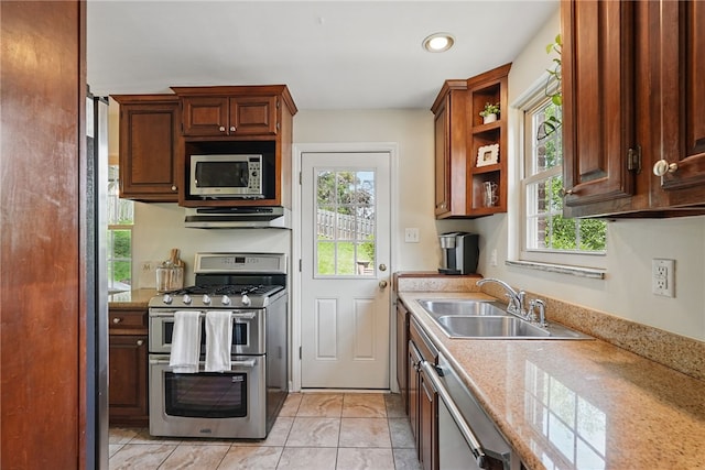 kitchen with a sink, light countertops, stainless steel appliances, and under cabinet range hood