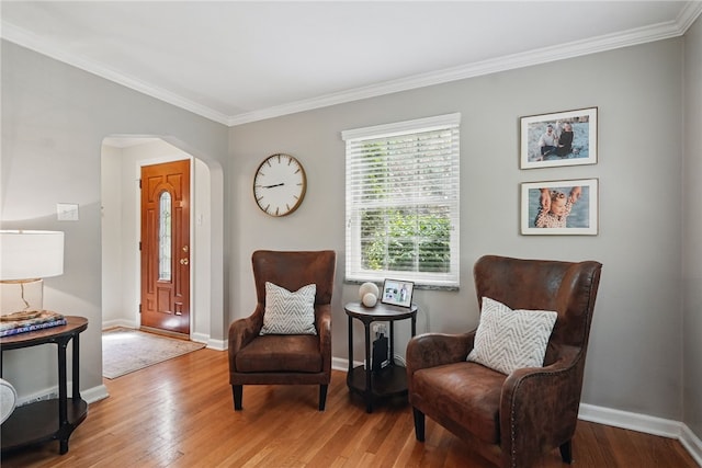 living area featuring arched walkways, ornamental molding, baseboards, and hardwood / wood-style floors