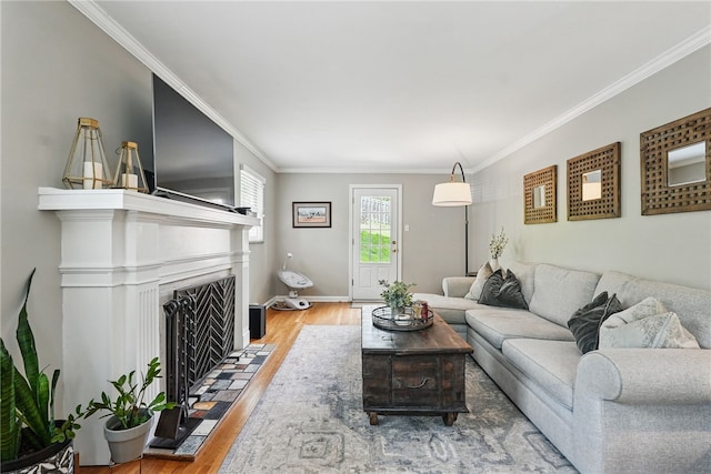 living room with crown molding, baseboards, a tiled fireplace, and wood finished floors