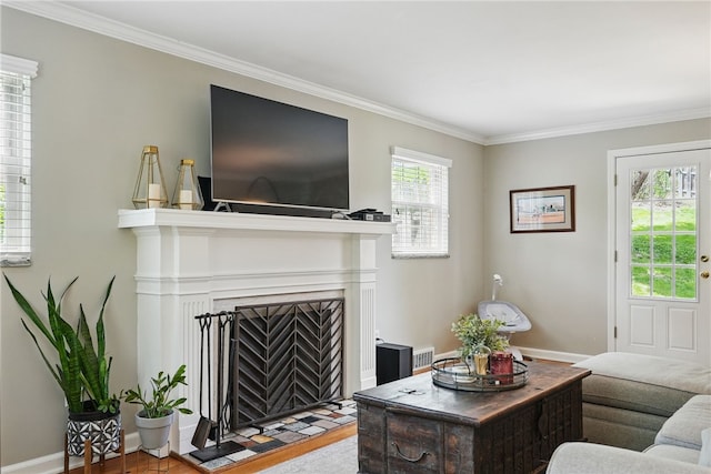 living area featuring crown molding, visible vents, wood finished floors, baseboards, and a fireplace with flush hearth