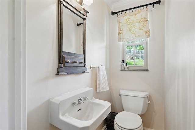 half bathroom with a sink, baseboards, and toilet