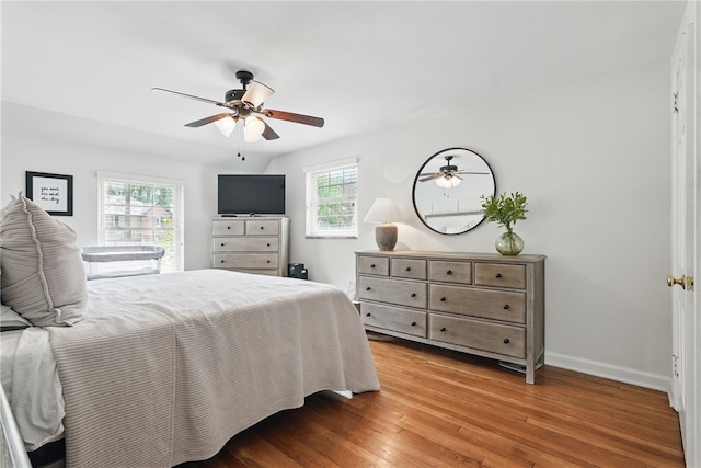 bedroom with light wood-style floors, baseboards, multiple windows, and ceiling fan