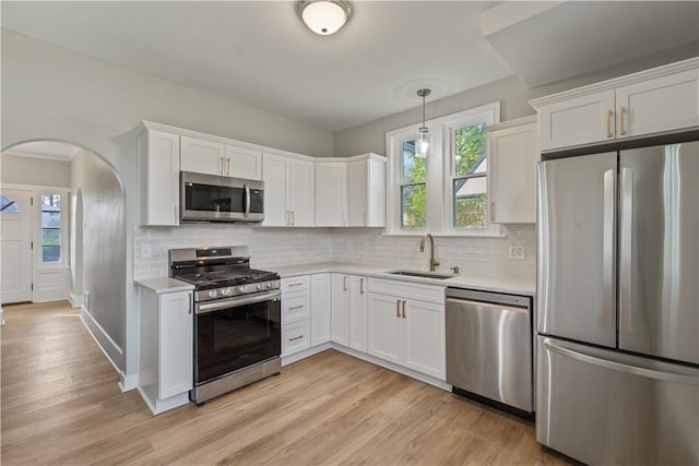 848 Ohio Ave, Monaca, PA 15061 - kitchen featuring light countertops, arched walkways, white cabinets, a sink, and appliances with stainless steel finishes