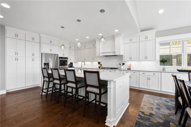 kitchen featuring white cabinets, a breakfast bar area, light countertops, stainless steel appliances, and dark wood-type flooring