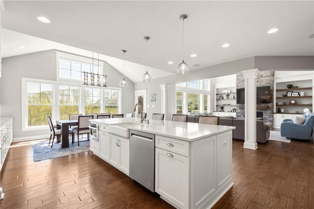 kitchen with stainless steel dishwasher, a sink, decorative columns, and dark wood finished floors