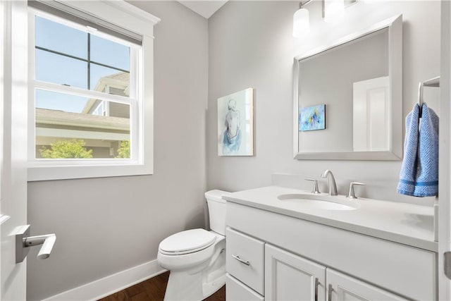 half bath featuring toilet, baseboards, plenty of natural light, and wood finished floors