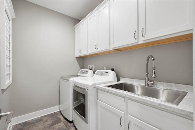 clothes washing area with cabinet space, independent washer and dryer, baseboards, and a sink