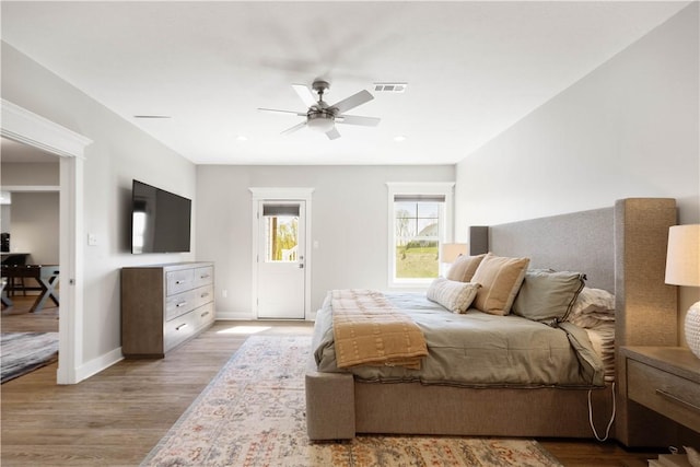 bedroom featuring a ceiling fan, baseboards, visible vents, and wood finished floors