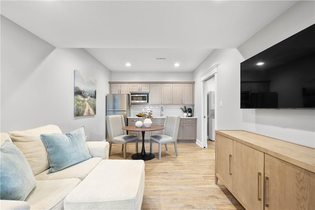 living room with recessed lighting, light wood-style flooring, and visible vents
