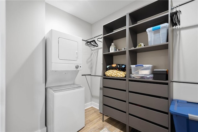 walk in closet with stacked washer and clothes dryer and light wood-style flooring