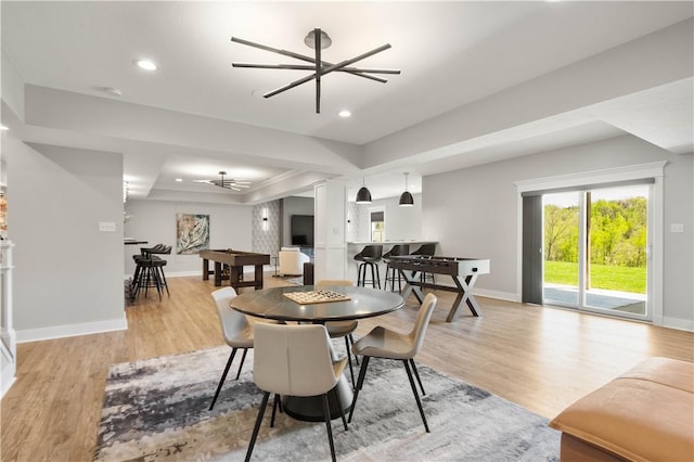 dining area featuring a tray ceiling, ceiling fan, baseboards, and light wood finished floors