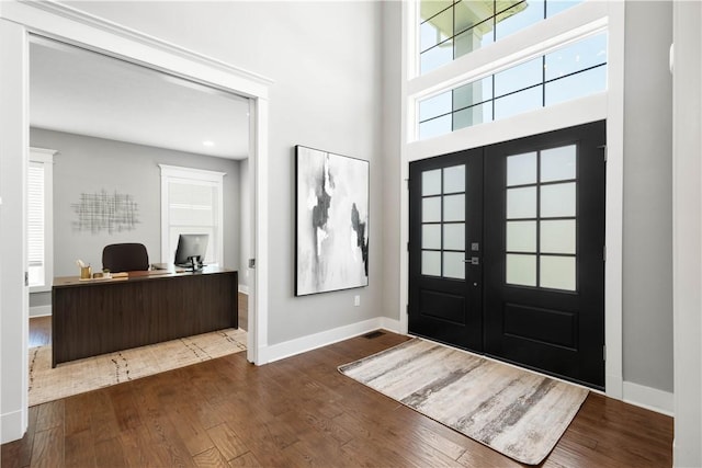 entrance foyer featuring baseboards, french doors, a towering ceiling, and dark wood-type flooring