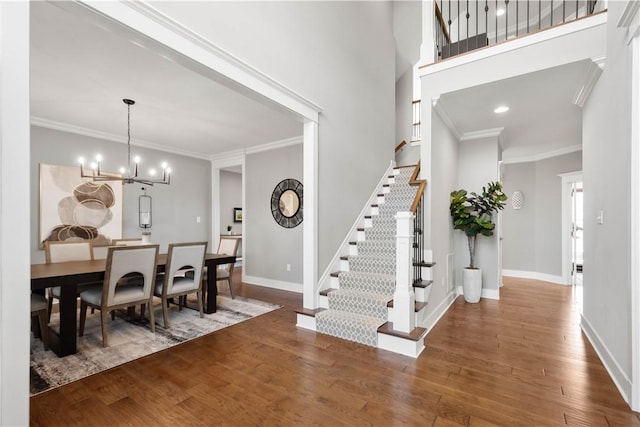foyer with baseboards, ornamental molding, stairs, and wood finished floors