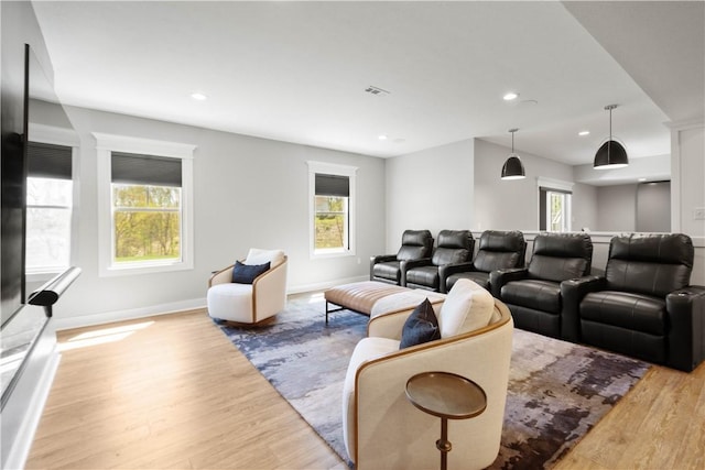 living area with baseboards, visible vents, a healthy amount of sunlight, and light wood-type flooring
