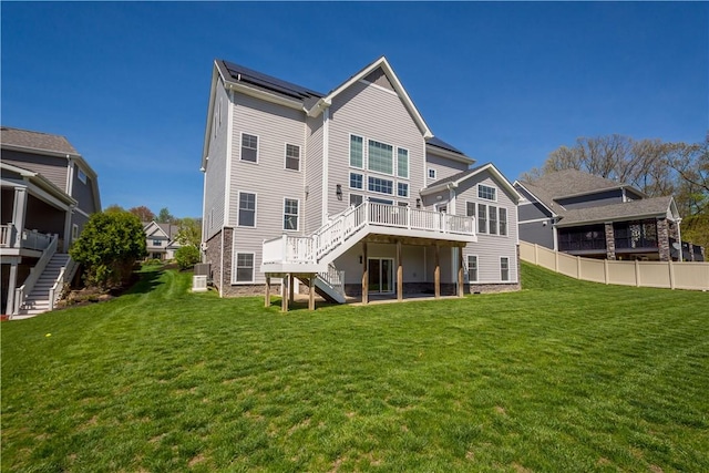 rear view of house with a lawn, fence, stairs, and a deck