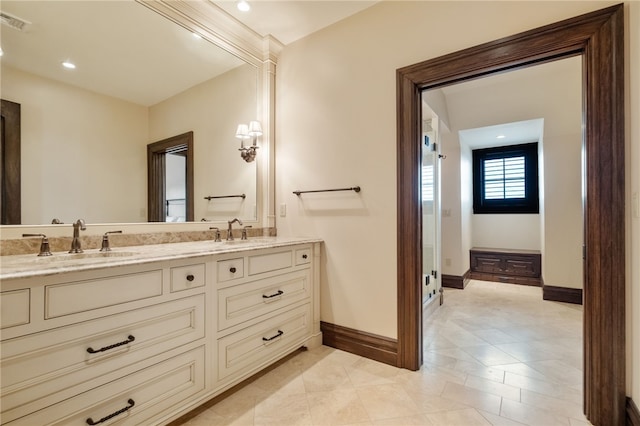 full bath with double vanity, baseboards, visible vents, and a sink