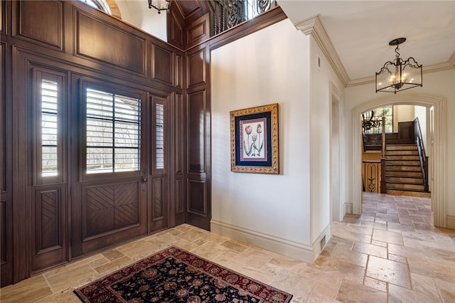 foyer with baseboards, arched walkways, stone tile flooring, and a chandelier