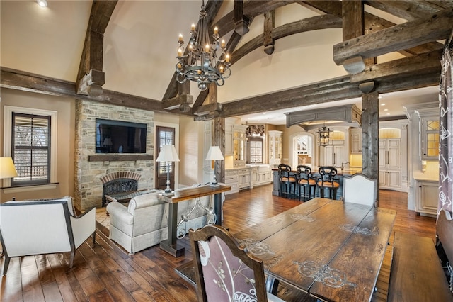 dining space with an inviting chandelier, dark wood-style floors, a fireplace, and beamed ceiling