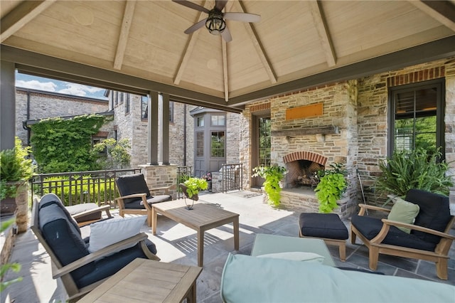 view of patio with a ceiling fan, an outdoor living space with a fireplace, and a gazebo