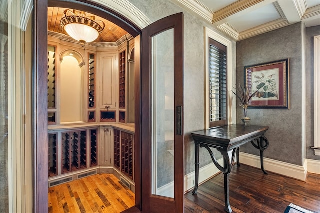 wine cellar featuring visible vents, ornamental molding, hardwood / wood-style floors, baseboards, and arched walkways