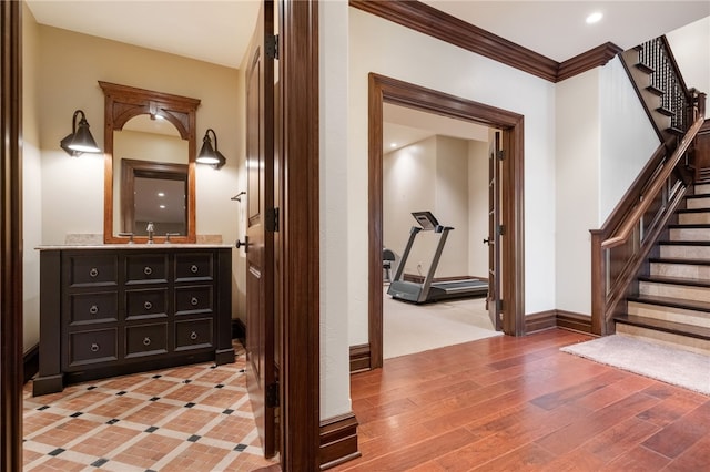 hall with crown molding, stairway, baseboards, a sink, and recessed lighting