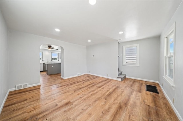 empty room featuring stairway, a wealth of natural light, light wood-type flooring, and visible vents
