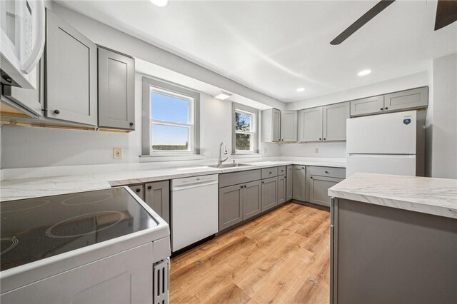 kitchen featuring white appliances, ceiling fan, recessed lighting, gray cabinets, and a sink