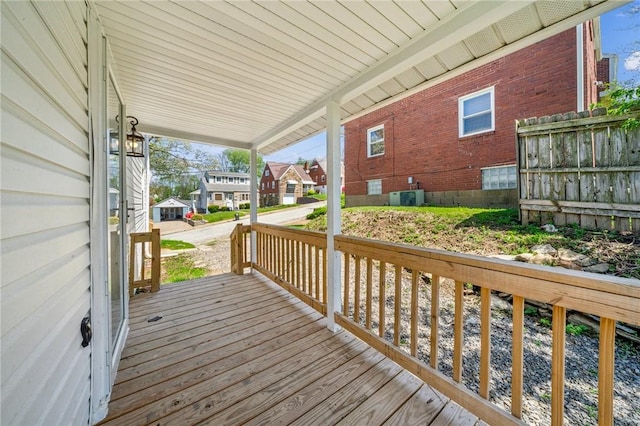 wooden deck featuring a residential view, covered porch, and central AC unit