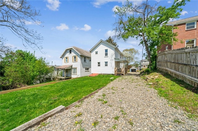 rear view of property featuring fence and a lawn