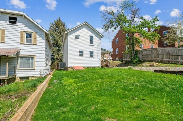 rear view of house with a lawn, fence, and central air condition unit