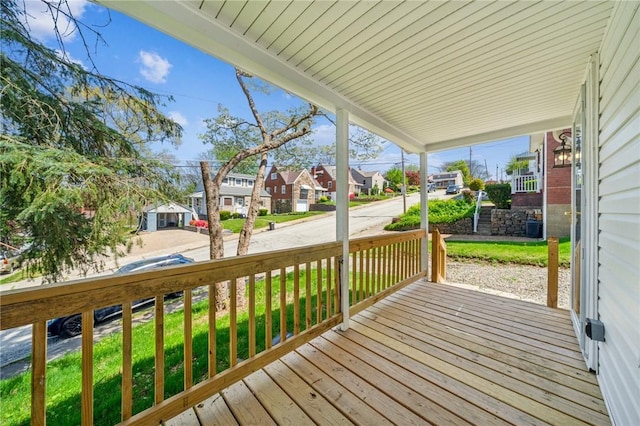 wooden terrace featuring a porch, a lawn, and a residential view