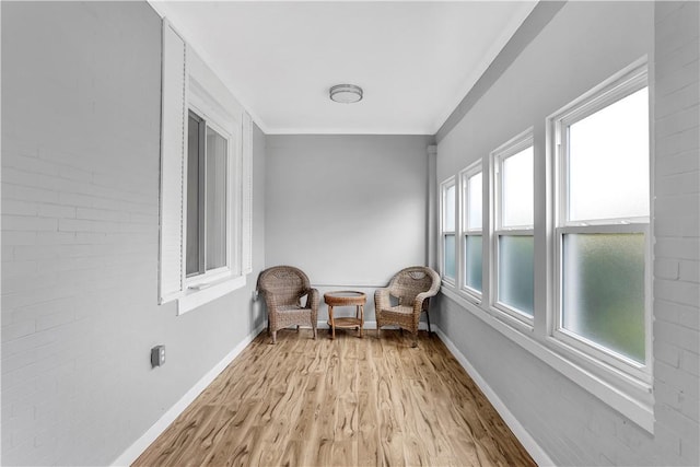 living area featuring crown molding, baseboards, and light wood-style flooring