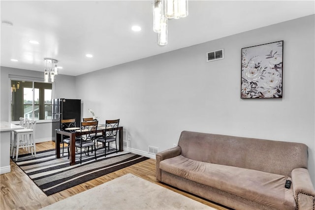 living area with baseboards, visible vents, and wood finished floors