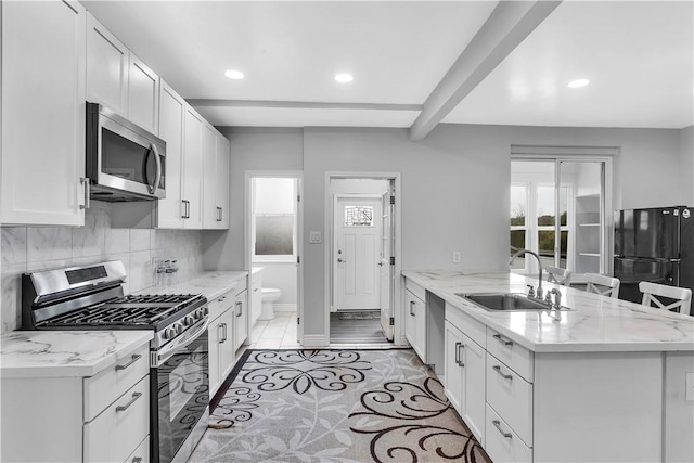 kitchen with a sink, appliances with stainless steel finishes, a peninsula, and a healthy amount of sunlight