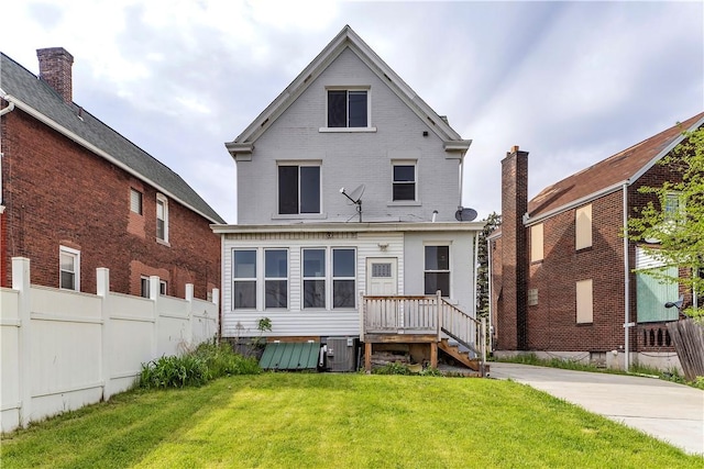 back of house with a lawn, central air condition unit, brick siding, and fence