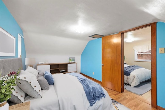 bedroom with wood finished floors and lofted ceiling