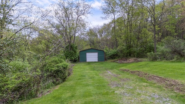 view of yard with a view of trees, an outdoor structure, and a garage