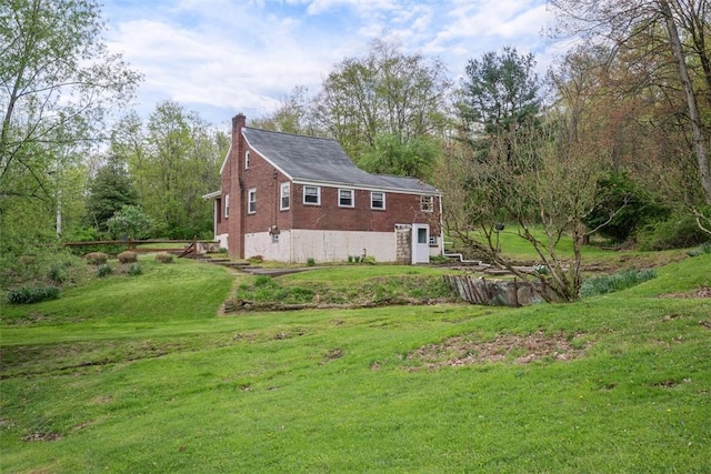 view of home's exterior with a yard, brick siding, and a chimney