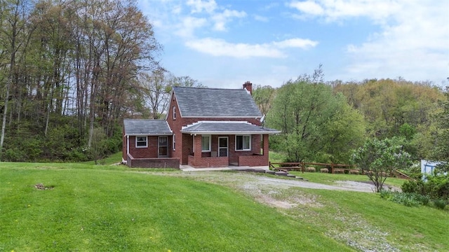 view of front of house with brick siding, a chimney, a front yard, and a porch
