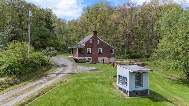 view of property exterior featuring a view of trees, a yard, and driveway