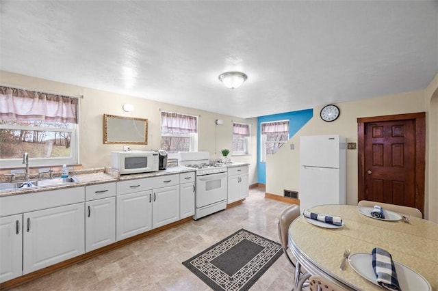 kitchen featuring visible vents, white appliances, light countertops, white cabinetry, and a sink