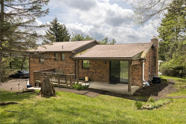 back of property with a wooden deck, a chimney, a yard, and brick siding