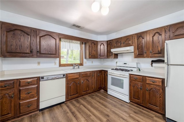 kitchen featuring visible vents, white appliances, light countertops, under cabinet range hood, and a sink